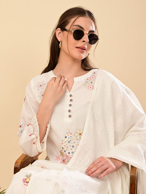 Woman wearing a white embroidered outfit with sunglasses on a beige background